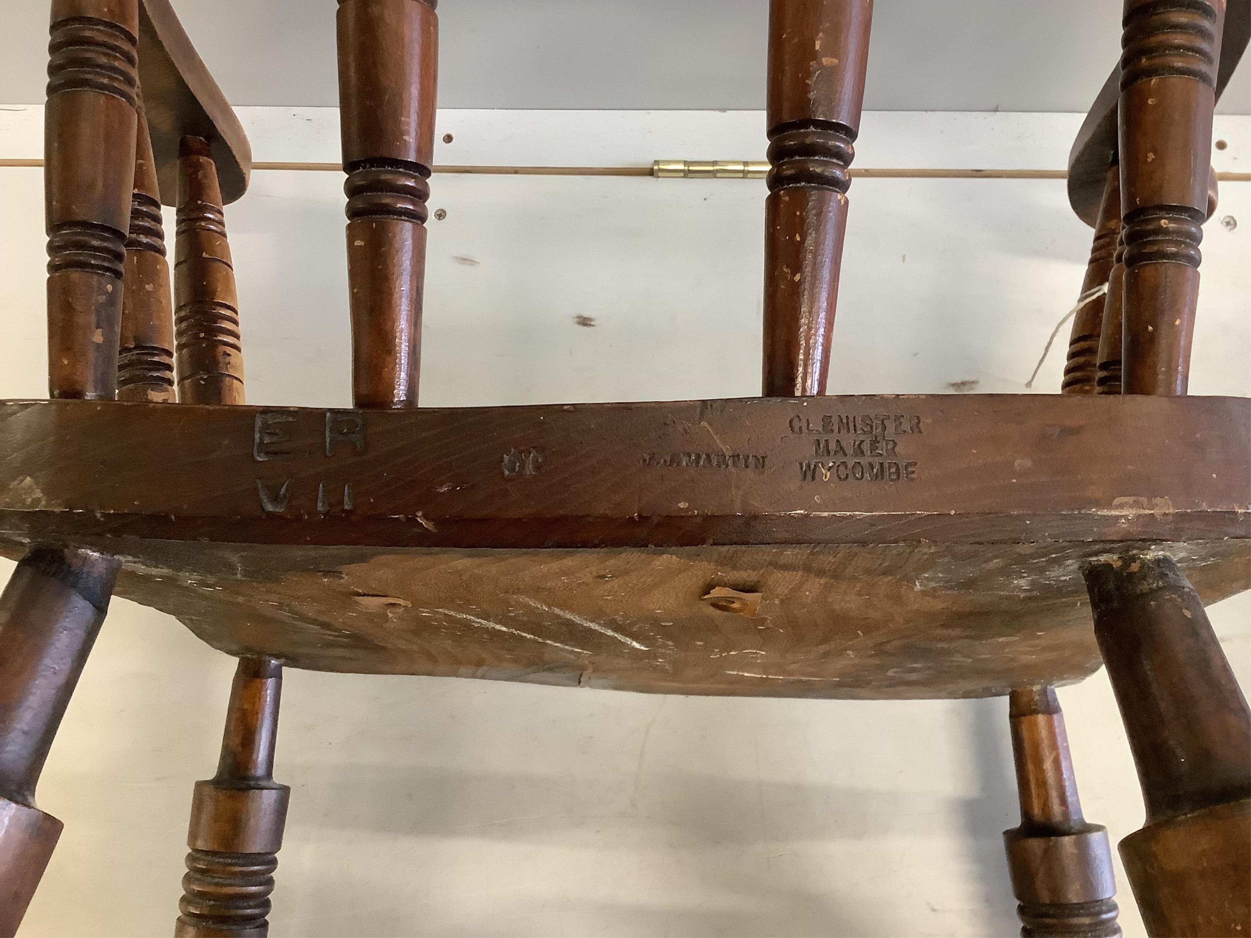 A pair of early 20th century elm and beech smokers bow chairs by Glenister, Wycombe, one bears Edward VII cypher, width 59cm, depth 48cm, height 84cm. Condition fair, one seat has cushion foam residue, the other split ve